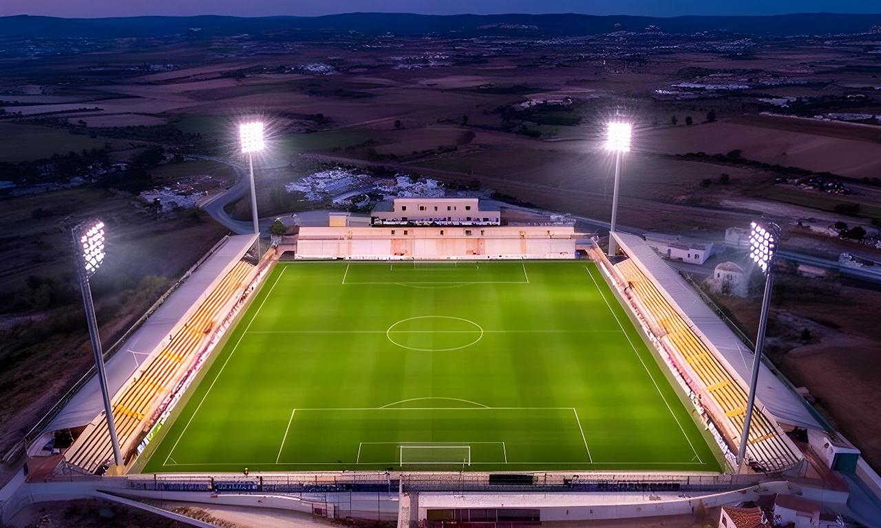Vista aérea de un campo de fútbol de césped natural con focos profesionales al anochecer en Huétor Tájar